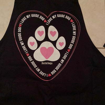 This print is a big heart drawn from two thin lines, a light pink and dark pink. On the inside edges of the heart all around the entire heart is repeated phrase ”I love my  guide dog.” In the center of the heart is the paw print in white of a Labrador retriever. In the center of each of the pads of the paw print is a pink heart.