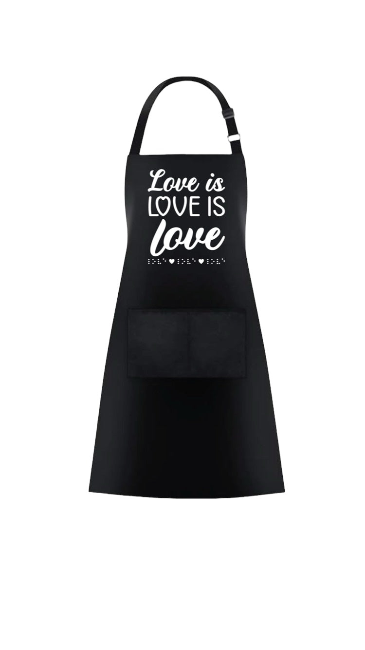 “Love is love is love” black 37-inch heavy duty cotton apron with long string ties and pull over the head strap. There are two big patch pockets on the front. The chest area has 3D puff print ink reading LOVE IS LOVE IS LOVE stacked one above the other in two beautiful fonts, complete with 3D tactile braille underneath the font.