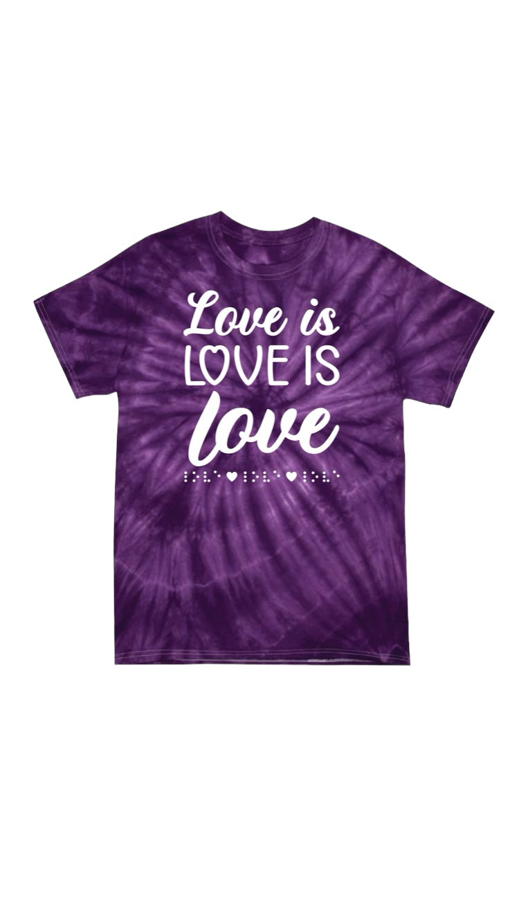 “Love is love is love” t-shirt with colorful tones of purple tie dye. The shirt has 3D puff print ink reading LOVE IS LOVE IS LOVE stacked one above the other in two beautiful fonts, complete with 3D tactile braille underneath the font.