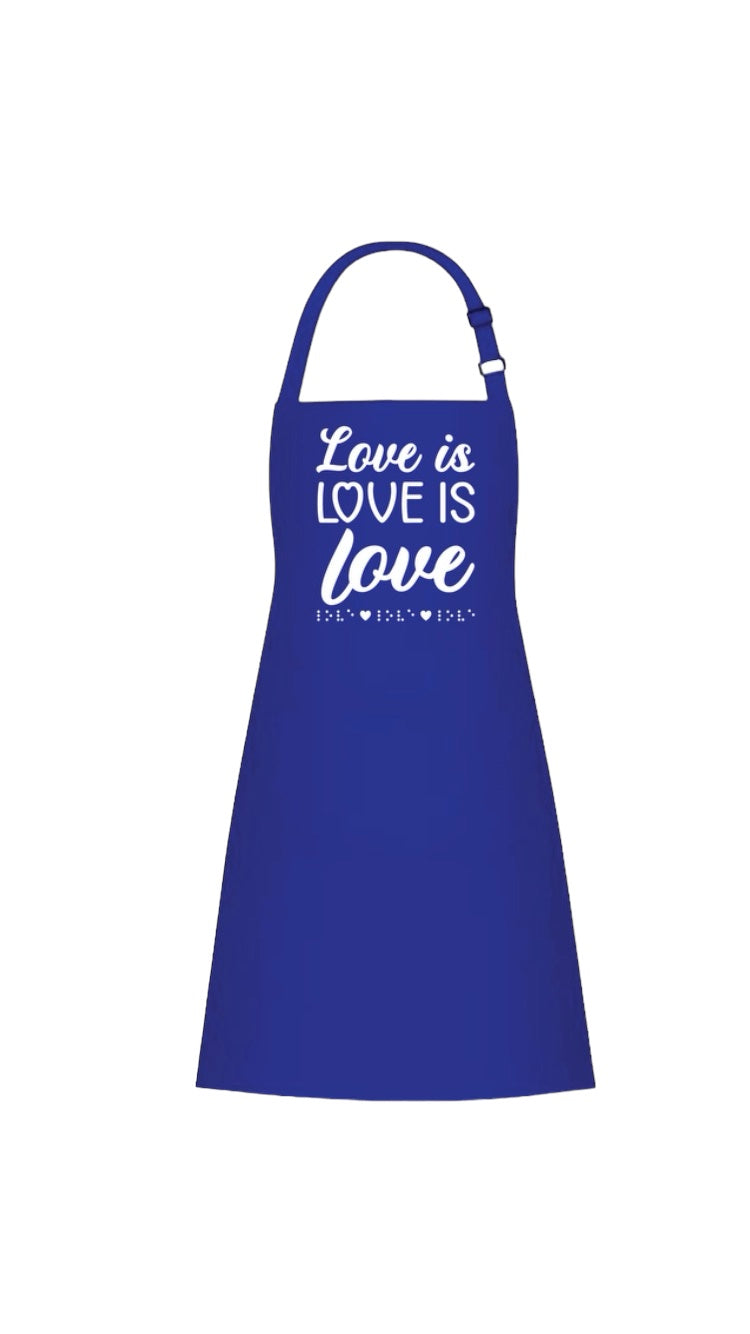“Love is love is love” royal blue 37-inch heavy duty cotton apron with long string ties and pull over the head strap. There are two big patch pockets on the front. The chest area has 3D puff print ink reading LOVE IS LOVE IS LOVE stacked one above the other in two beautiful fonts, complete with 3D tactile braille underneath the font. 