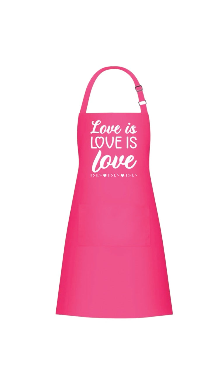 “Love is love is love” bright pink 37-inch heavy duty cotton apron with long string ties and pull over the head strap. There are two big patch pockets on the front. The chest area has 3D puff print ink reading LOVE IS LOVE IS LOVE stacked one above the other in two beautiful fonts, complete with 3D tactile braille underneath the font.