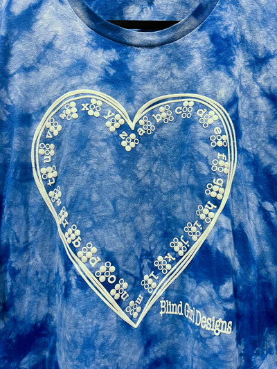 This light blue, blue, and white tie-dye shirt features the Braille ABCs lining the inside of a hand-drawn heart. It's printed in our puff ink so that it is tactile! 