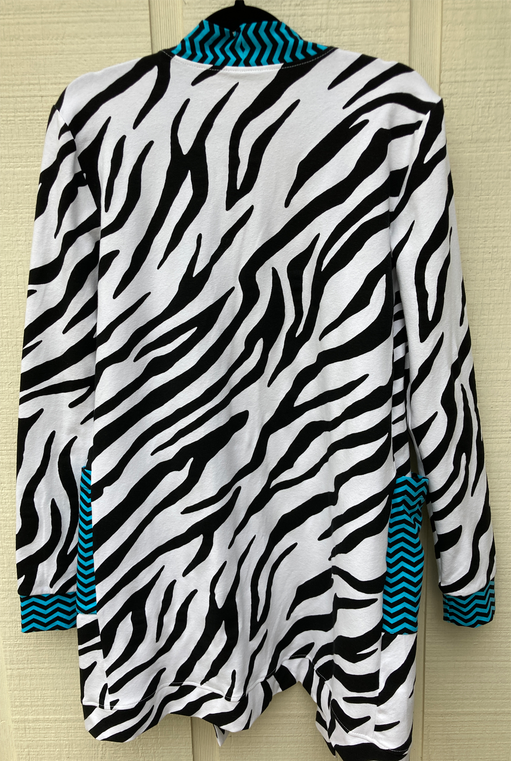 Shows the whole back of the cardigan with electric blue and navy chevron striped edging with black and white zebra body.