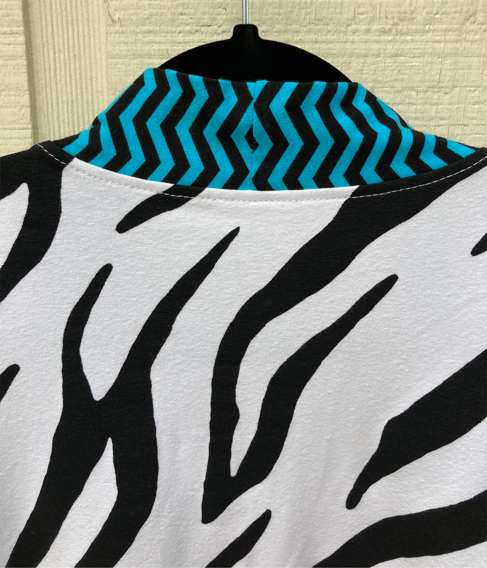 Close up of the back of the cardigan with electric blue and navy chevron striped edging with black and white zebra body.
