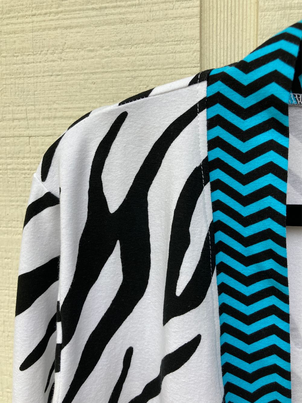 Close up of the arm of the cardigan with electric blue and navy chevron striped edging with black and white zebra body.