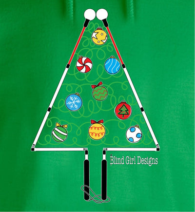 There is a large colorful chest print of a whimsical Christmas tree outlined by two blind canes, folded at the joints to make a triangle tree shape on the front of this green t-shirt. The handles form the trunk and the roller balls form the outline of the top of the tree. The inside of the tree has green squiggles to suggest light strands with red, yellow, white, and blue ornaments shaped like a roller ball on the bottom of a cane.